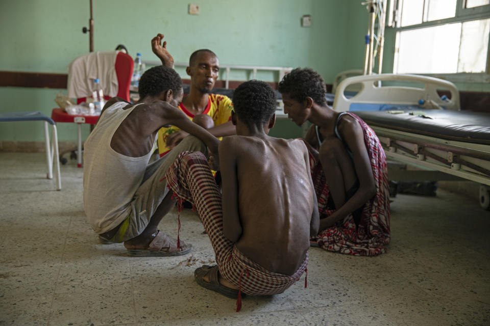 In this Aug. 1, 2019 photo, Ethiopian migrants, from center background to right, Gamal Hassan, Abdu Yassin, Mohammed Hussein, and Abdu Mohammed, who were imprisoned by traffickers for months, eat rice from a bowl on the floor, at the Ras al-Ara Hospital in Lahj, Yemen. They said they were fed once a day with scraps of bread and a sip of water when they were held. (AP Photo/Nariman El-Mofty)