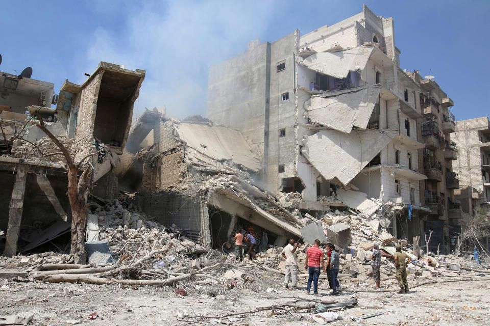 Men inspect a damaged site after double airstrikes