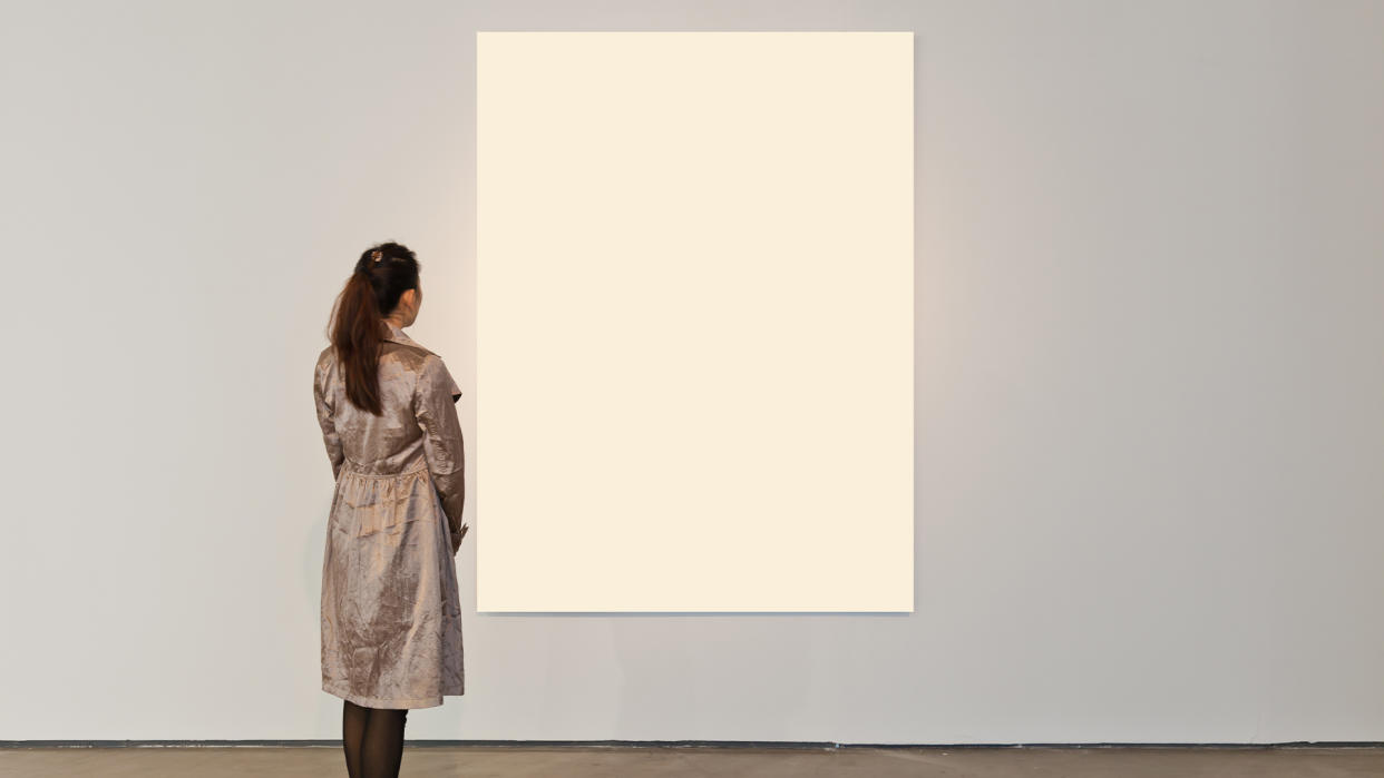  Woman at an art gallery looking at a plain white canvas. 