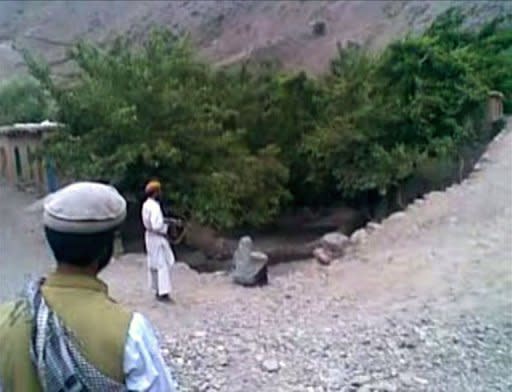 A frame grab shows a man pointing an AK47 rifle at a 22 year old woman named as Najiba (C), who is sitting on the edge of a ditch shortly before being executed by gunfire in Qol village, Parwan province, north of Kabul. Najiba was married to a member of a hardline Taliban militant group and was accused of adultery with a Taliban commander