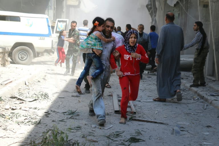 A Syrian family runs for cover amid the rubble of destroyed buildings following a reported air strike in Aleppo, on April 29, 2016