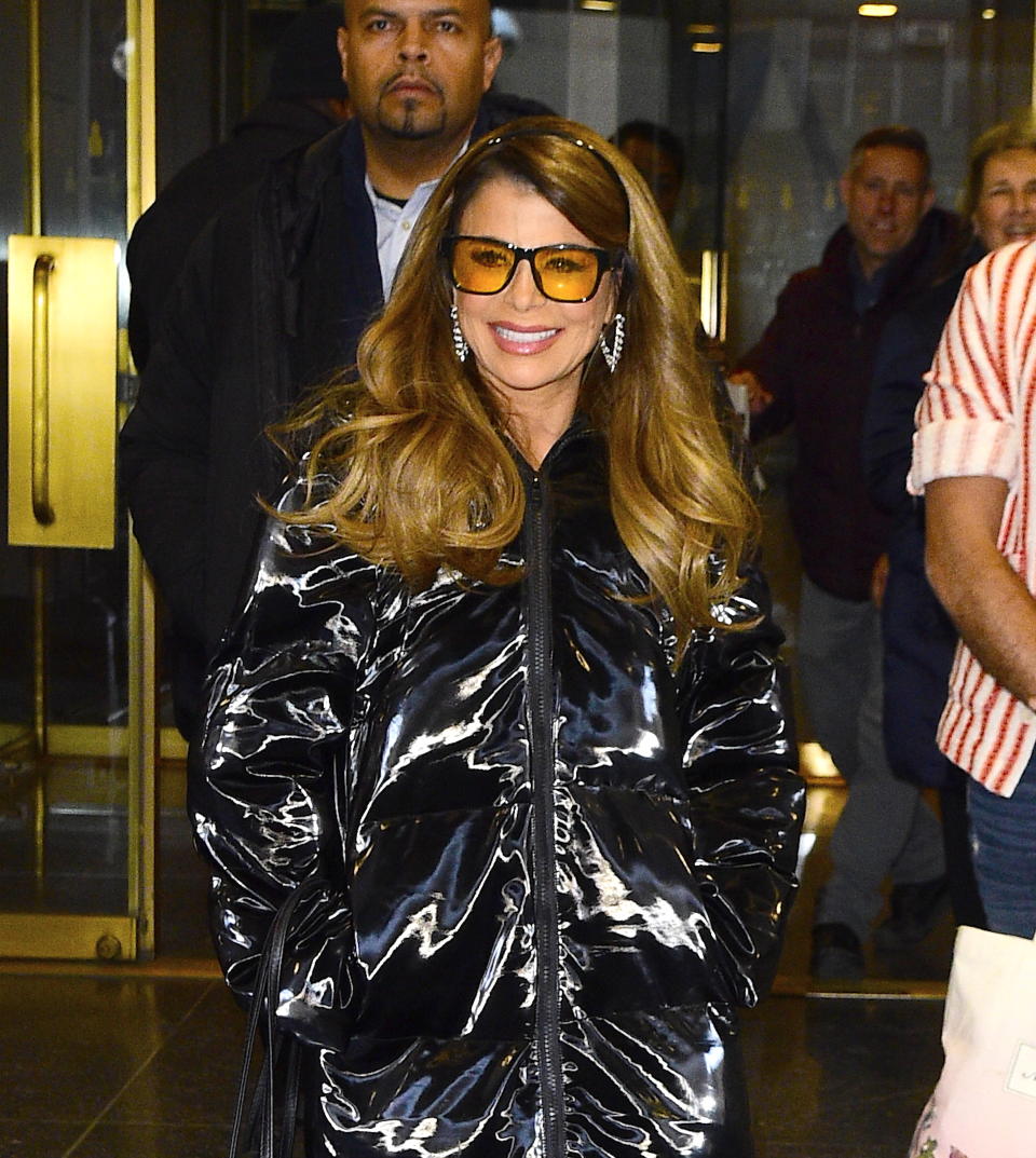 Close-up of Paula smiling and wearing a shiny coat and sunglasses