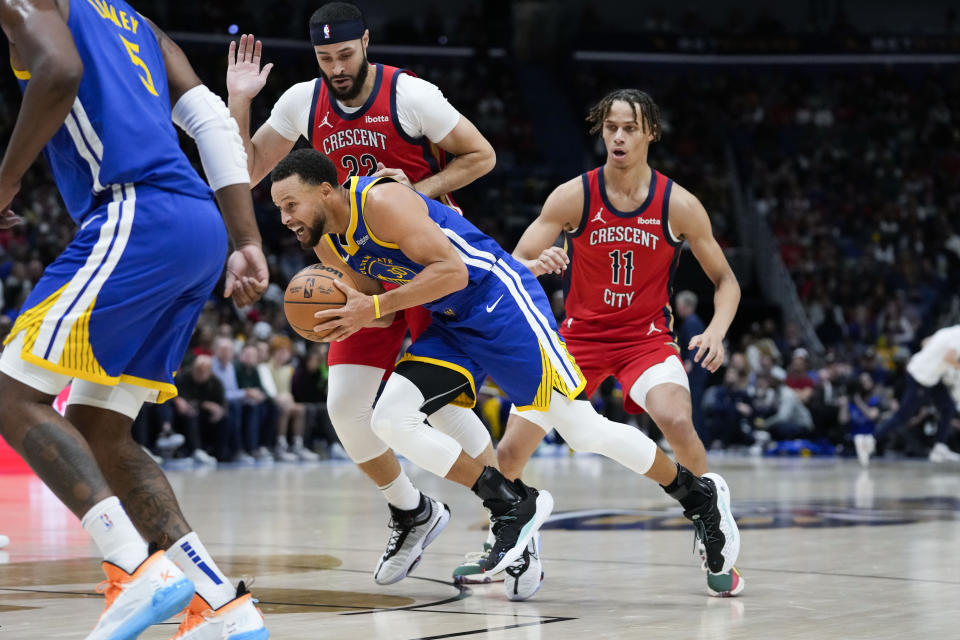 Golden State Warriors guard Stephen Curry drives to the basket against New Orleans Pelicans forward Larry Nance Jr. and guard Dyson Daniels (11) in the first half of an NBA basketball game in New Orleans, Monday, Oct. 30, 2023. (AP Photo/Gerald Herbert)