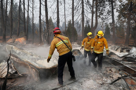 FILE PHOTO: Firefighters move debris while recovering human remains from a trailer home destroyed by the Camp Fire in Paradise, California, U.S., November 17, 2018. REUTERS/Terray Sylvester