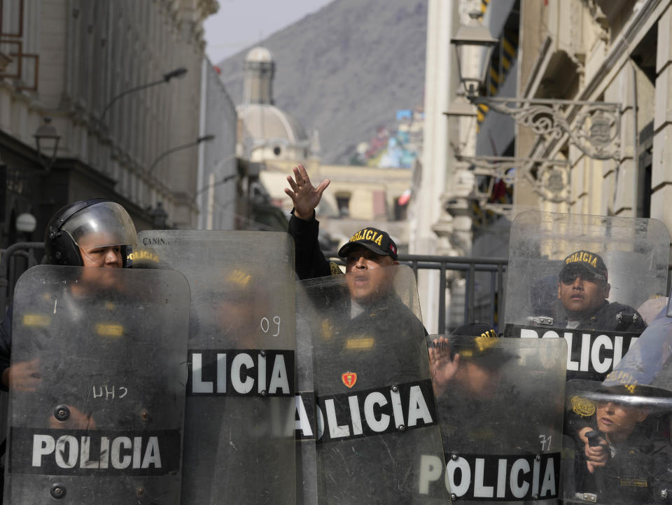 Police in riot gear ask for back-up as the clash with anti-government protesters who traveled to the capital from across the country to march against Peruvian President Dina Boluarte in Lima, Peru, Thursday, Jan. 19, 2023. Protesters are seeking immediate elections, Boluarte's resignation, the release of ousted President Pedro Castillo and justice for up to 48 protesters killed in clashes with police. (AP Photo/Martin Mejia)