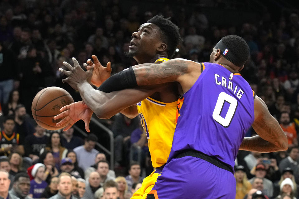 Phoenix Suns forward Torrey Craig (0) fouls Los Angeles Lakers center Thomas Bryant, left, during the first half of an NBA basketball game, Monday, Dec. 19, 2022, in Phoenix. (AP Photo/Rick Scuteri)