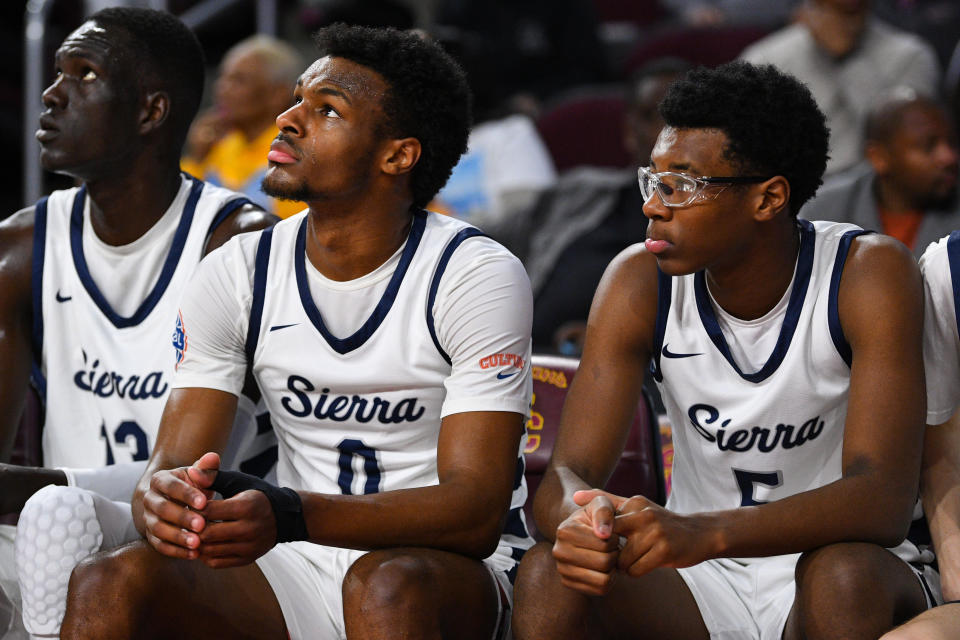 Bryce James (R) sits on the bench next to his older brother Bronny James during a Sierra Canyon game last season. Bryce James transferred back to Sierra Canyon after a circuitous summer and made his junior season debut Wednesday. (Photo by Brian Rothmuller/Icon Sportswire via Getty Images)