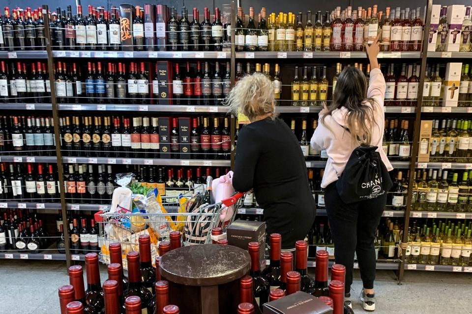 A woman reaches for a bottle of wine in a supermarket. Photo: Martin Bernetti/AFP via Getty