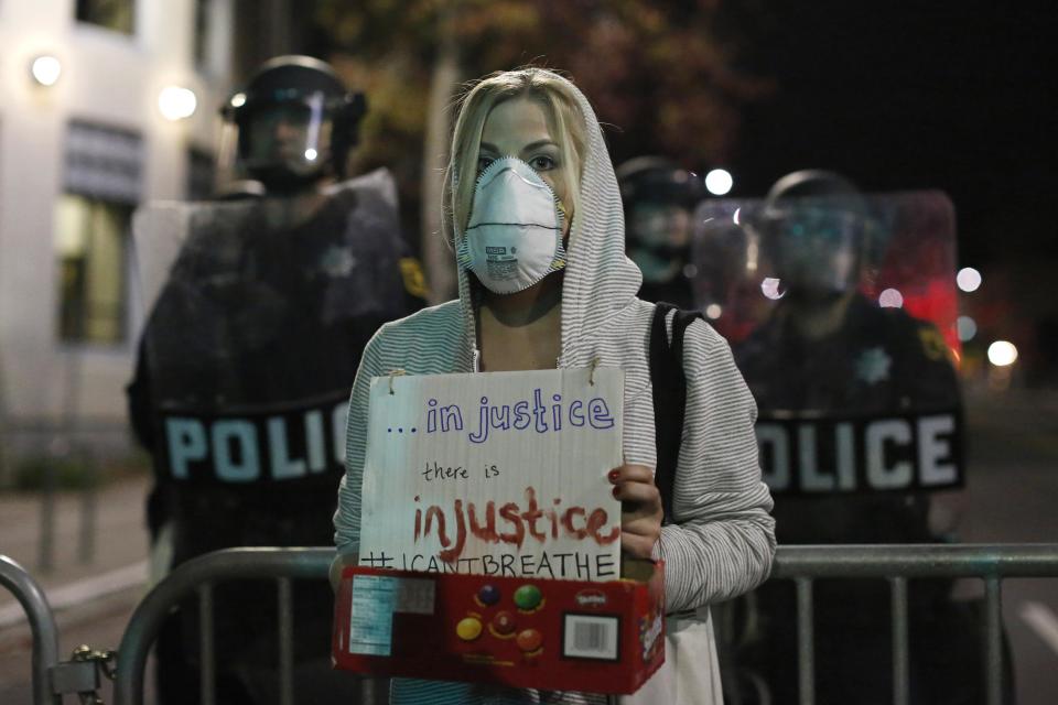 Alyson Reimer, a graduate student at the University of California Berkeley school of law, holds a sign in front of a police line during a march against the New York City grand jury decision to not indict in the death of Eric Garner in Berkeley, California December 8, 2014. Cities across the United States have seen large protests in recent nights following a grand jury's decision not to charge an officer in the July killing of Garner. An unarmed black father of six, Garner died after police put him in a banned chokehold. REUTERS/Stephen Lam (UNITED STATES - Tags: POLITICS CIVIL UNREST CRIME LAW)