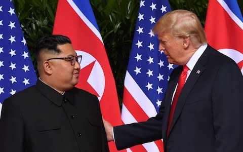 Donald Trump pats the arm of Kim Jong-un after shaking his hand - Credit: AFP