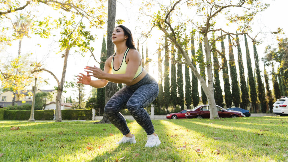 Woman practicing jump squats in a park