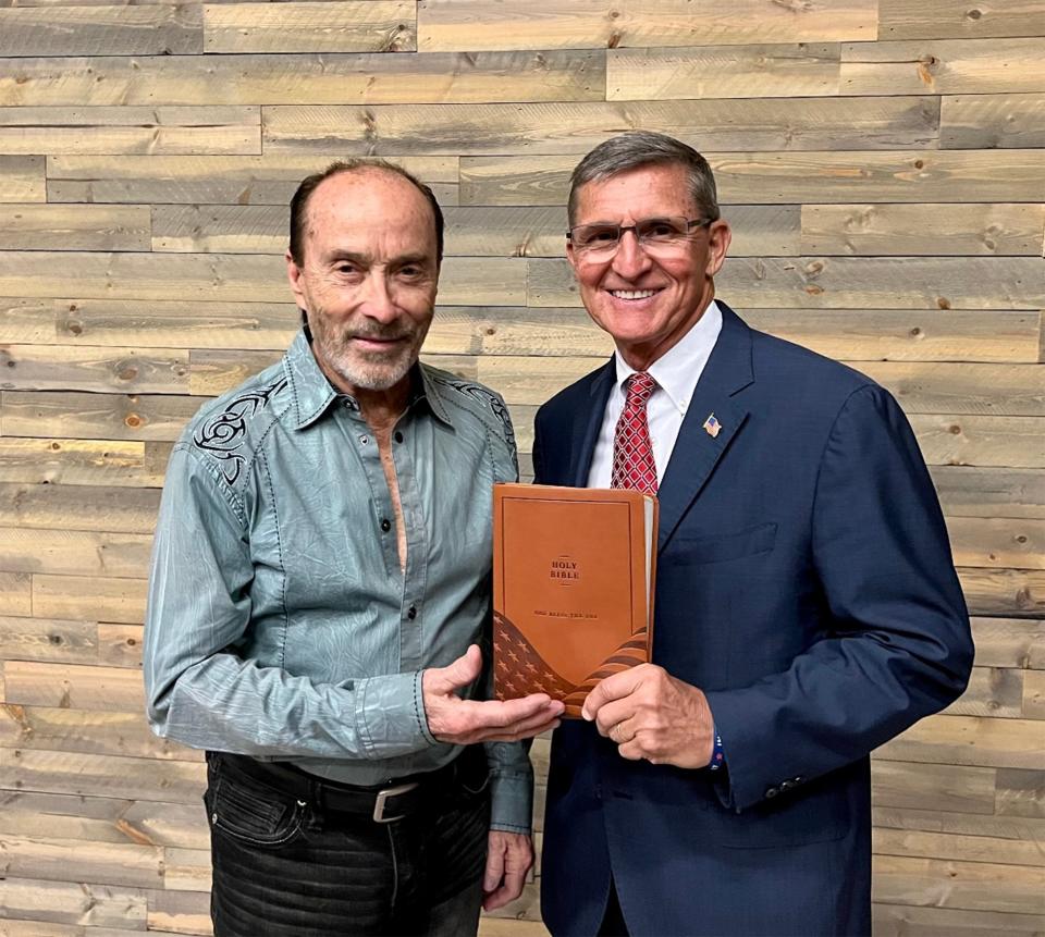 Lee Greenwood presenting a Bible with the Constitution, The Declaration of Independence, The Pledge of Allegiance and the song "God Bless the USA" to General Mike Flynn.