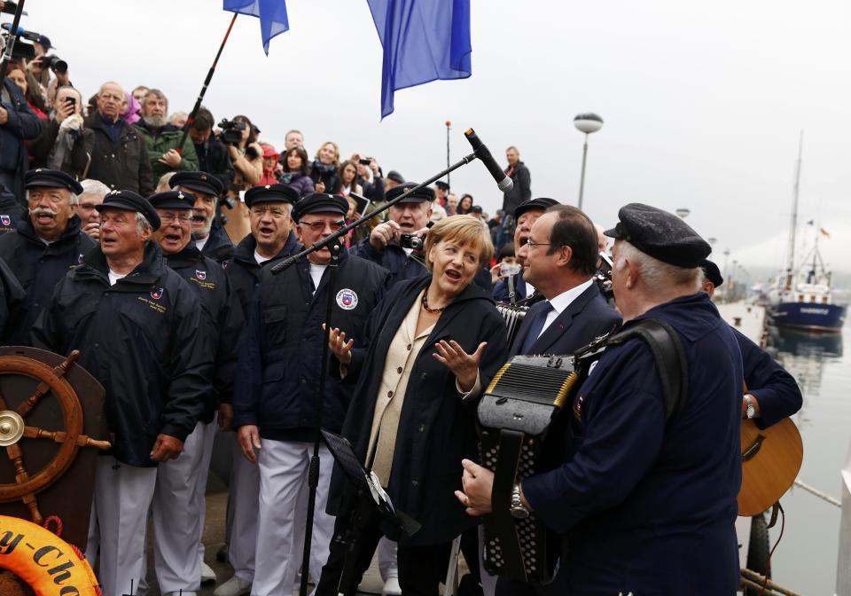 German Chancellor Angela Merkel, 3rd right, and French President Francois Hollande, 2nd right, listen to a Shanty choir before embarking on the ship Nordwind in Sassnitz on Ruegen island in the Baltic sea, Germany, Friday, May 9, 2014. (AP Photo/Thomas Peter, Pool)