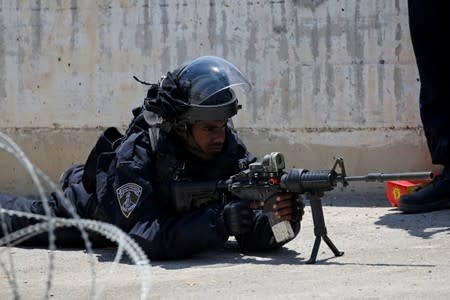 Israeli policeman aims a weapon during clashes with Palestinians at a protest against Bahrain's workshop for U.S. peace plan, near Hebron, in the Israeli-occupied West Bank