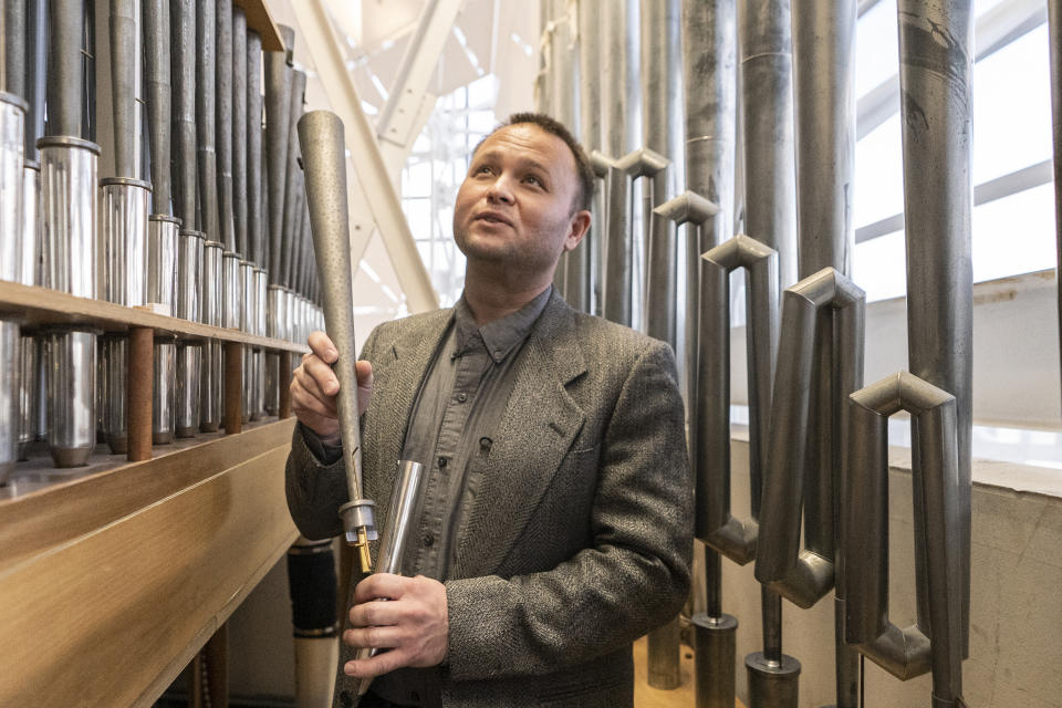 Kevin Cartwright, technician and president of Los Angeles-based Rosales Organ Builders, holds one of the pipes of the Hazel Wright organ at Christ Cathedral in Garden Grove, Calif., Tuesday, Feb. 15, 2022. Nearly a decade and $3 million later, “Hazel” is back in the shimmering sanctuary and heavenly chords from her pipes are once again ringing out in its vaulted nave. (AP Photo/Damian Dovarganes)