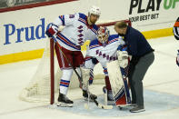 New York Rangers goaltender Alexandar Georgiev, center, is helped off the ice by Pavel Buchnevich, left, and another rangers staff member during the first period of the NHL hockey game against the New Jersey Devils in Newark, N.J., Sunday, April 18, 2021. (AP Photo/Seth Wenig)