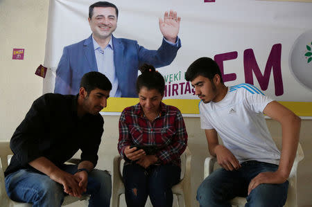 People watch a video announcing the first election rally of Selahattin Demirtas, jailed former leader of pro-Kurdish opposition Peoples' Democratic Party (HDP), which was posted to social media by his party and shows Demirtas' wife Basak Demirtas during her phone call with his husband accompanied by her relatives, in an election office of HDP in Yesilalan village of Mardin province, Turkey June 6, 2018. REUTERS/Sertac Kayar