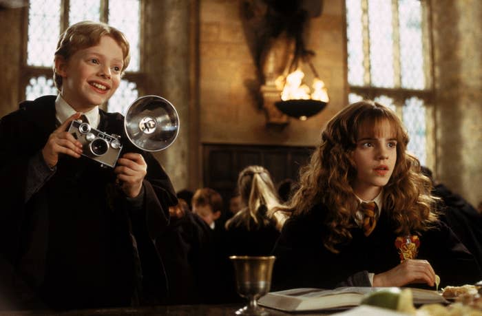 Colin and Hermione Granger in Hogwarts' Great Hall with a camera