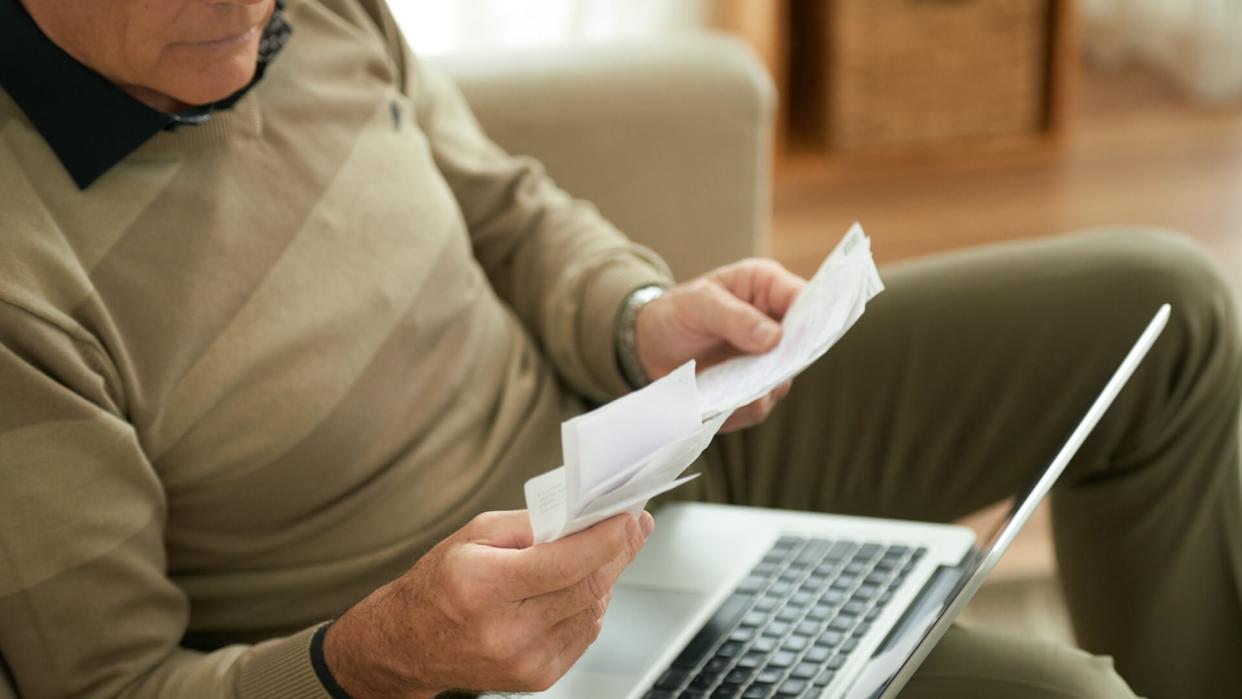 Aged man checking bills he need to pay online.