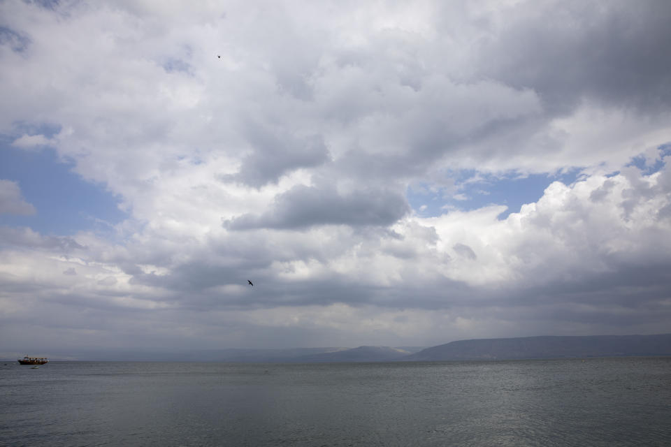 In this Saturday, April 25, 2020 photo, birds fly while an empty tourist ship is anchored in the Sea of Galilee, locally known as Lake Kinneret. After an especially rainy winter, the Sea of Galilee in northern Israel is at its highest level in two decades, but the beaches and major Christian sites along its banks are empty as authorities imposed a full lockdown. (AP Photo/Ariel Schalit)