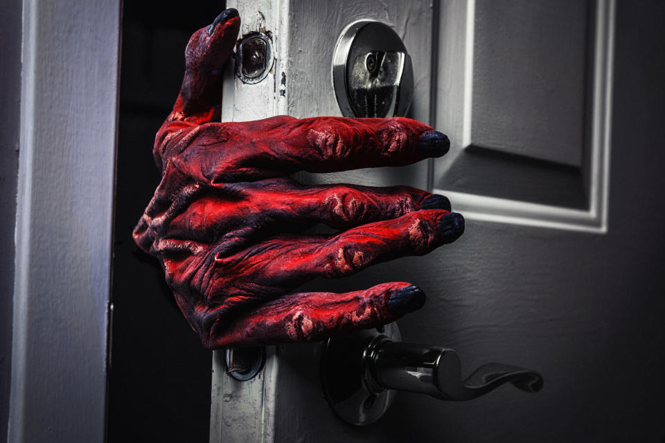 Red and black monster hand door knocker on a grey door