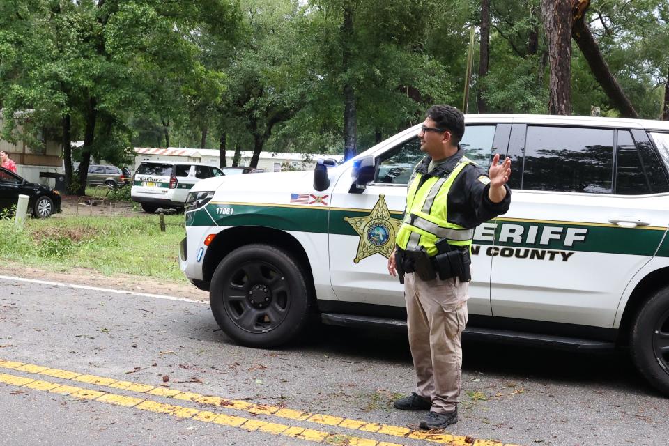 A Leon County Sheriff's Office deputy, Deputy Garcia, monitors traffic on Aenon Church Road in front of a home where a woman died after her house was struck by a falling tree during severe thunderstorms Friday morning.