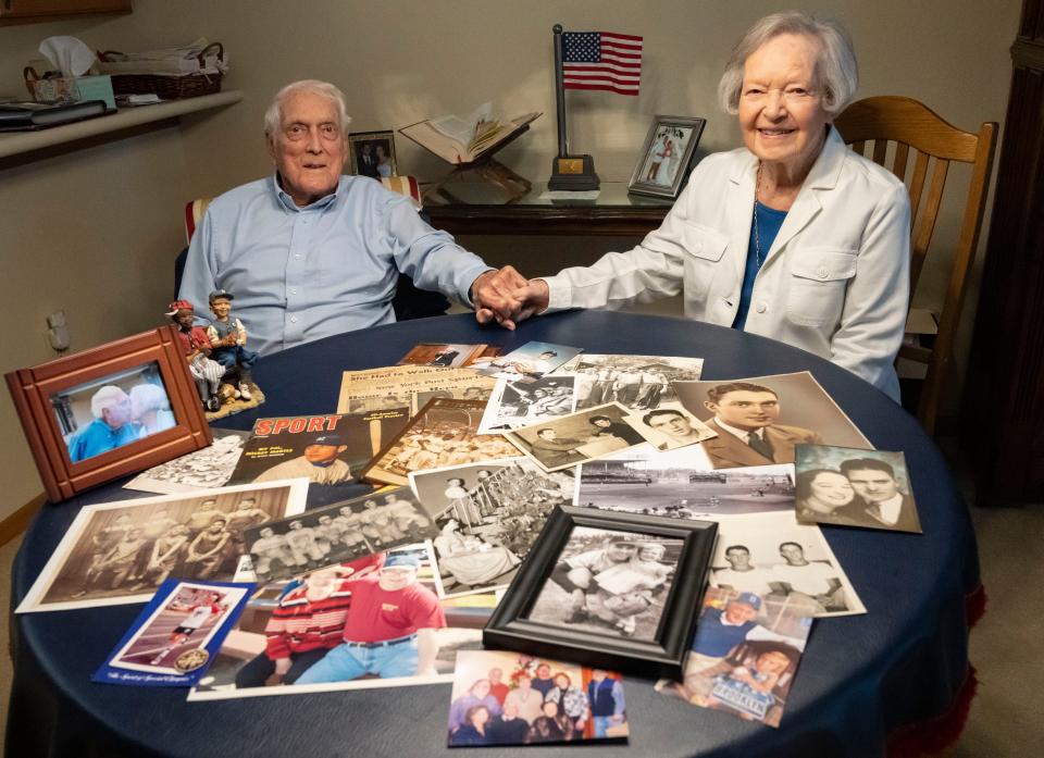 Carl Erskine (left) holds the hand of his wife Betty as old images lay scattered on their dining room table on Friday, August 5, 2022 at the Primrose Retirement Community in Anderson. 