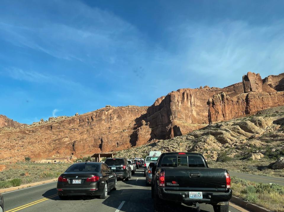 The entrance and a line of cars at Arches National Park.