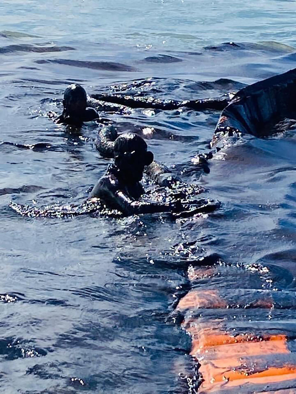 This photo taken and provided by Georges de La Tremoille of Mu Press shows divers using a containment boom to help contain oil leaking from the MV Wakashio, a bulk carrier ship that recently ran aground off the southeast coast of Mauritius, Friday, Aug. 7, 2020. The Indian Ocean island of Mauritius declared a “state of environmental emergency” late Friday after a Japanese-owned ship that ran aground offshore days ago began spilling tons of fuel. (Georges de La Tremoille/MU Press via AP)