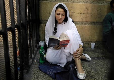 Aya Hijazi, founder of a non-governmental organisation that looks after street children, sits reading a book inside a holding cell as she faces trial on charges of human trafficking, sexual exploitation of minors, and using children in protests, at a courthouse in Cairo, Egypt March 23, 2017. REUTERS/Mohamed Abd El Ghany