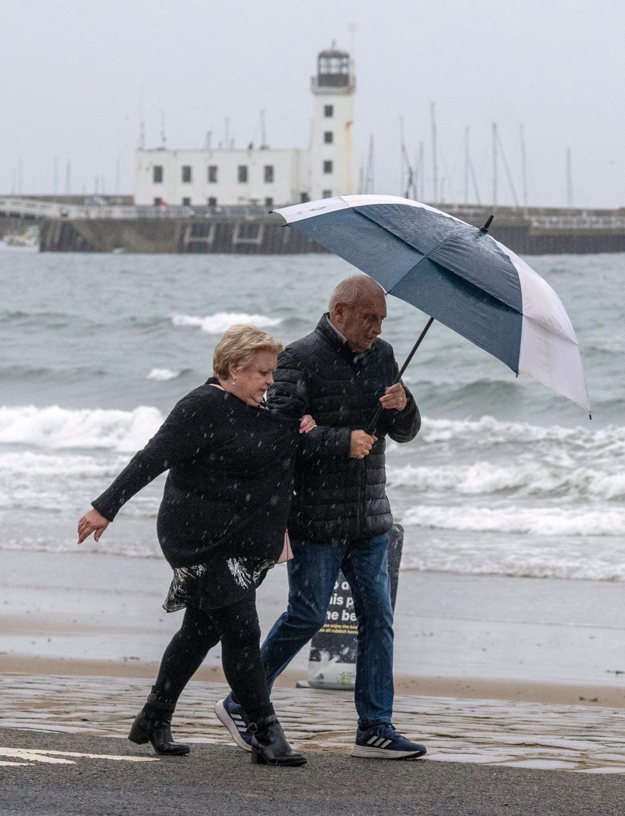 People walk along Scarborough sea front during Storm Agnes (PA)