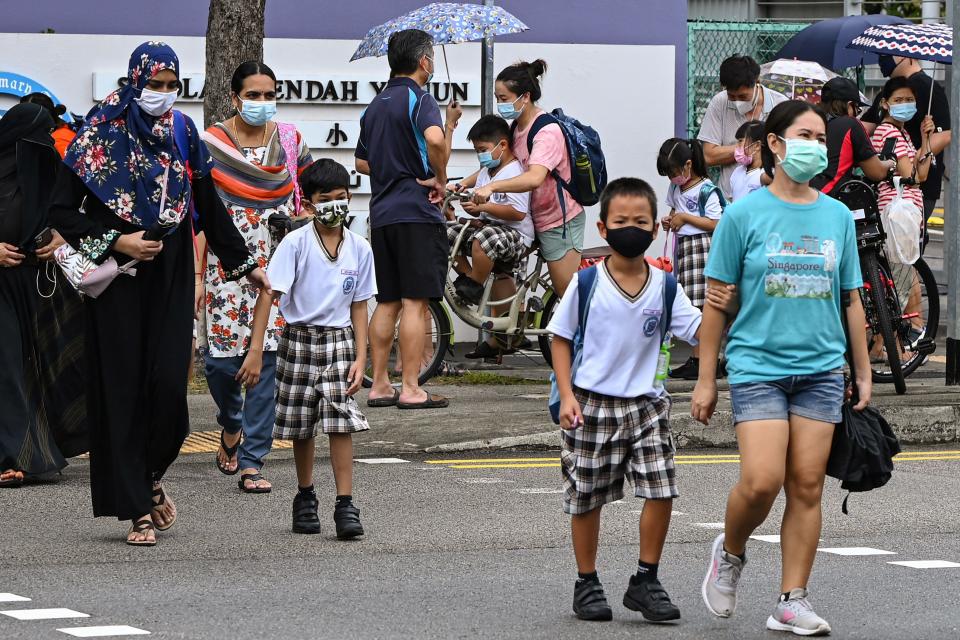 Children walk home with their guardians after school in Singapore on May 17, 2021, as the country prepares to shut all schools and switch to home-based learning until the end of the term due to a rise in the number of Covid-19 coronavirus cases. (Photo by Roslan RAHMAN / AFP) (Photo by ROSLAN RAHMAN/AFP via Getty Images)