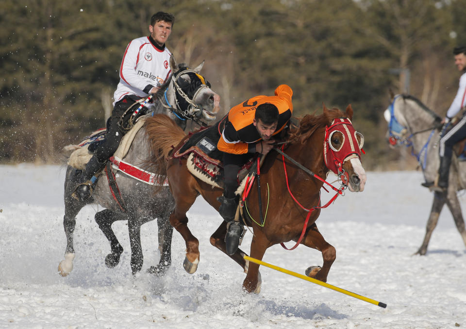 A rider dodges the javelin thrown by an opponent during a game of Cirit, a traditional Turkish equestrian sport that dates back to the martial horsemen who spearheaded the historical conquests of central Asia's Turkic tribes, between the Comrades and the Experts local sporting clubs, in Erzurum, eastern Turkey, Friday, March 5, 2021. The game that was developed more than a 1,000 years ago, revolves around a rider trying to spear his or her opponent with a "javelin" - these days, a rubber-tipped, 100 centimeter (40 inch) length of wood. A rider from each opposing team, which can number up to a dozen players, face each other, alternately acting as the thrower and the rider being chased. Cirit was popular within the Ottoman empire, before it was banned as in the early 19th century. However, its popularity returned as is now one of many traditional sports encouraged by the government and tournaments are often arranged during festivals or to celebrate weddings. (AP Photo/Kenan Asyali)