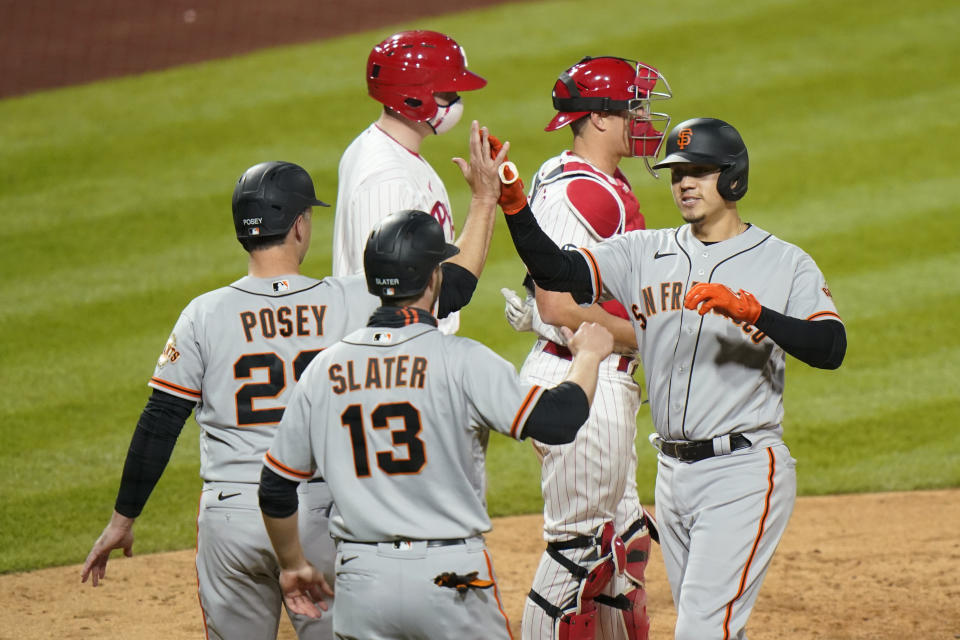 San Francisco Giants' Wilmer Flores, right, celebrates with Austin Slater, center, and Buster Posey, left, after hitting a three-run home run off Philadelphia Phillies pitcher Connor Brogdon during the eighth inning of a baseball game, Tuesday, April 20, 2021, in Philadelphia. (AP Photo/Matt Slocum)