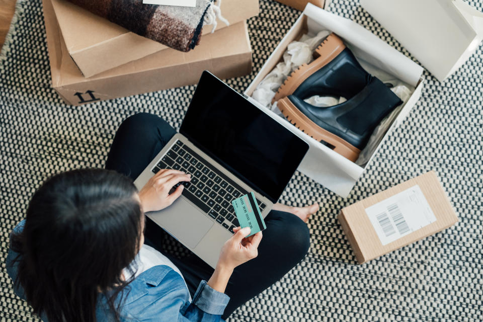 High angle view of a young Asian woman shopping online on laptop, making payment with credit card. Enjoying Seasonal sales. Shopaholic concept.