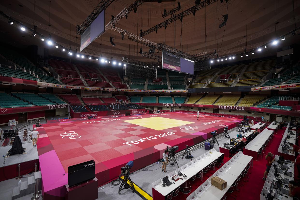 People prepare the field of play for judo at the Nippon Budokan at the Summer Olympics in Tokyo. (AP Photo/Vincent Thian