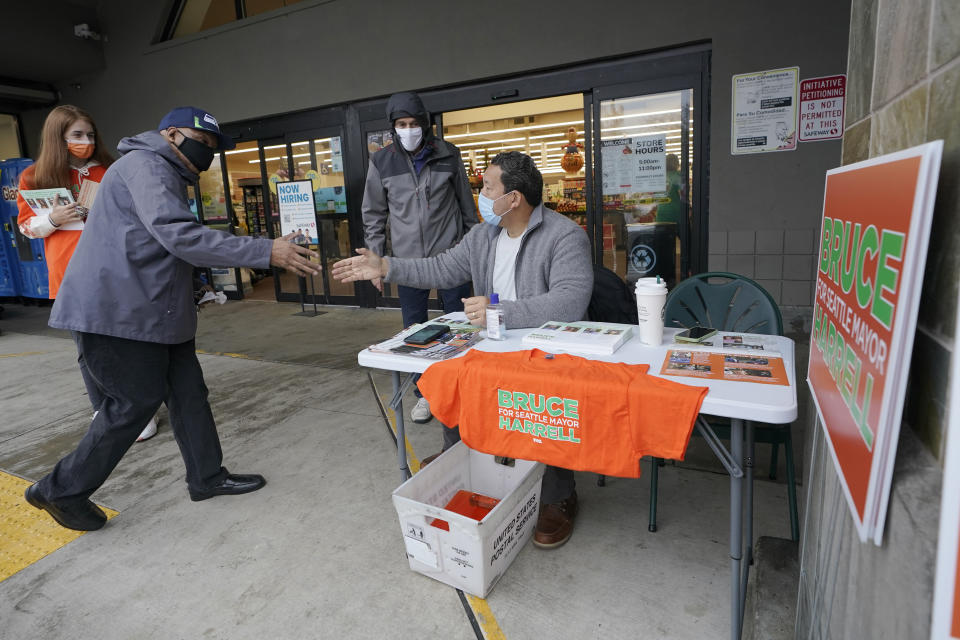 Bruce Harrell, center, who is running against Lorena Gonzalez in the race for Mayor of Seattle, shakes hands with shoppers as he campaigns Tuesday, Nov. 2, 2021, on Election Day at a grocery store in South Seattle. (AP Photo/Ted S. Warren)