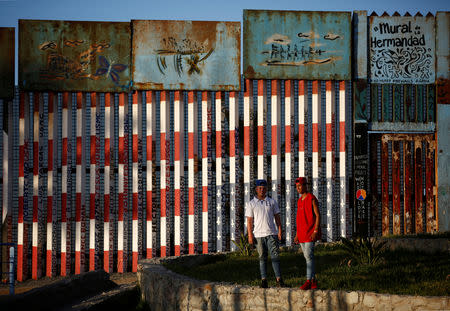 FILE PHOTO: Elmer Eduardo Bonilla Mendoza (L) and Carlos Alfredo Pavon Canelas, part of a caravan of thousands traveling from Central America en route to the United States, pose in front of the border wall between the U.S. and Mexico in Tijuana, Mexico, November 24, 2018. REUTERS/Kim Kyung-Hoon