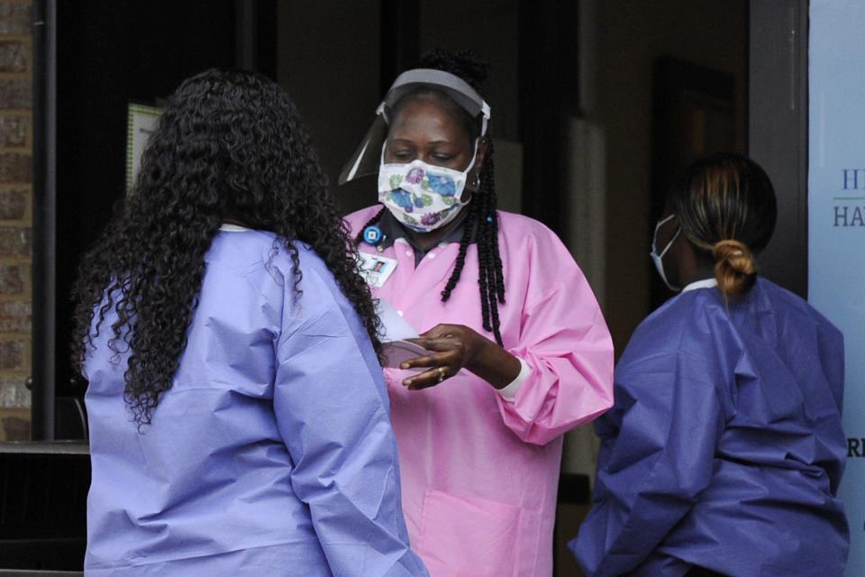 In this May 27, 2020, photo, health care workers talk outside a Lowndes County coronavirus testing site in Hayneville, Ala. Experts say Lowndes County and nearby poor, mostly black counties in rural Alabama are now facing a “perfect storm” as infections tick up: a lack of access to medical care combined with poverty and the attendant health problems that can worsen the outcomes for those who become sick. (AP Photo/Jay Reeves)