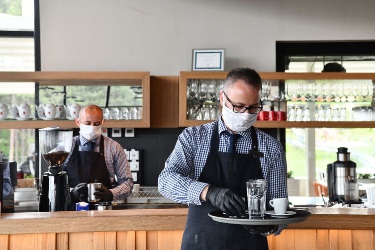 <span class="caption">Restaurants will need to employ new, more visible hygiene practices.</span> <span class="attribution"><a class="link " href="https://www.shutterstock.com/image-photo/waiter-medical-protective-mask-serves-coffee-1734664976" rel="nofollow noopener" target="_blank" data-ylk="slk:dotshock/Shutterstock;elm:context_link;itc:0;sec:content-canvas">dotshock/Shutterstock</a></span>