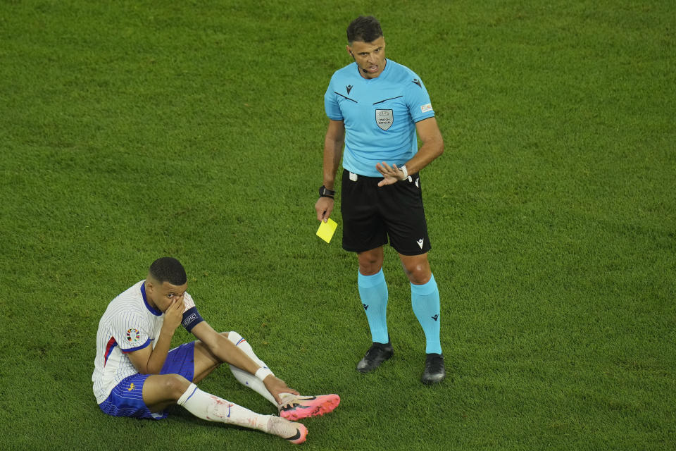 Referee Jesus Gil Manzano of Spain about to give a yellow card to Kylian Mbappe of France during a Group D match between Austria and France at the Euro 2024 soccer tournament in Duesseldorf, Germany, Monday, June 17, 2024. (AP Photo/Hassan Ammar)