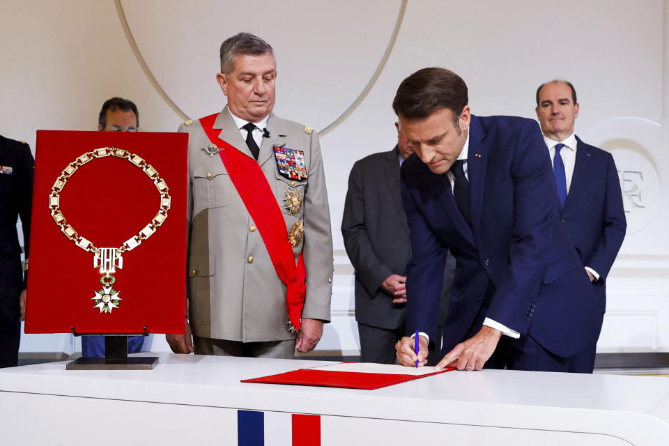 France's Military Chief of Staff to the presidency Benoit Puga, center, left, stands next to French President Emmanuel Macron signing a document during the ceremony of his inauguration for a second term at the Elysee palace, in Paris, France, Saturday, May 7, 2022. Macron was reelected for five years on April 24 in an election runoff that saw him won over far-right rival Marine Le Pen. (Gonzalo Fuentes/Pool via AP)