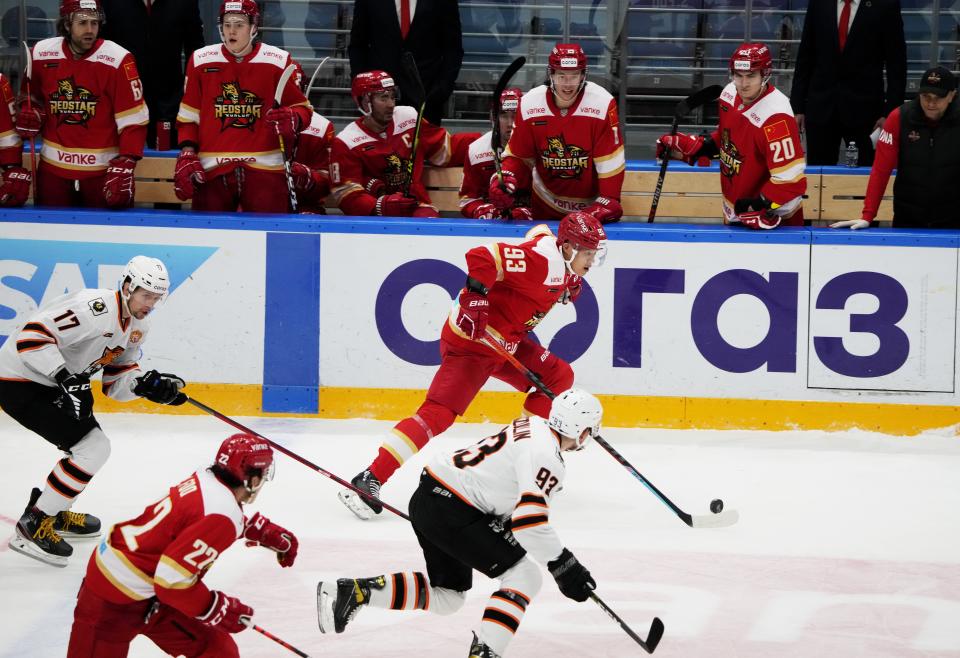 Kunlun Red Star's Zach Yuen, center, controls the puck during the Kontinental Hockey League ice hockey match between Kunlun Red Star Beijing and Amur Khabarovsk in Mytishchi, just outside Moscow, Russia, Monday, Nov. 15, 2021. Many of Kunlun Red Star's players are aiming to represent the Chinese national team at the Olympics in Beijing. (AP Photo/Alexander Zemlianichenko)