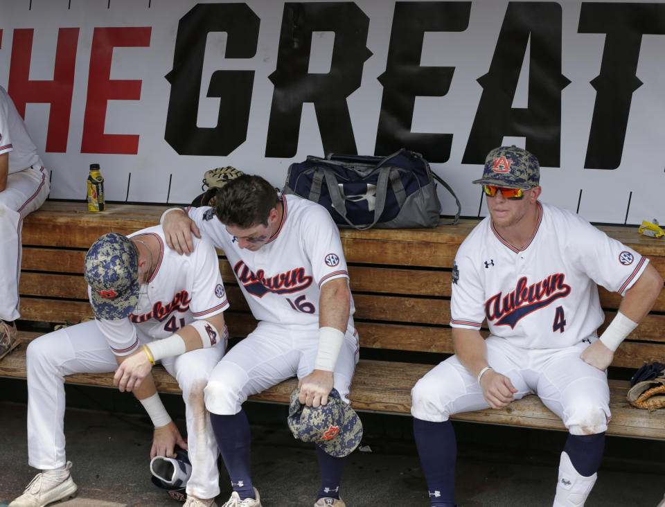 Auburn's Steven Williams (41), Kason Howell (16) and Rankin Woley (4) sit in the dugout following their 5-3 loss to Louisville, in an NCAA College World Series elimination baseball game in Omaha, Neb., Wednesday, June 19, 2019. (AP Photo/Nati Harnik)