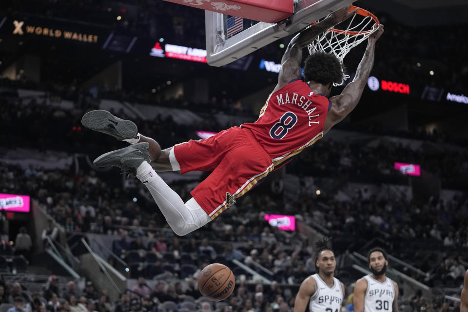 New Orleans Pelicans forward Naji Marshall (8) swings from the rim after scoring against the San Antonio Spurs during the second half of an NBA basketball game in San Antonio, Sunday, Dec. 17, 2023. (AP Photo/Eric Gay)