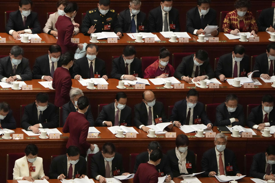 Hostesses refill drinking glasses for delegates during the opening session of China's National People's Congress (NPC) at the Great Hall of the People in Beijing, Sunday, March 5, 2023. (AP Photo/Ng Han Guan)