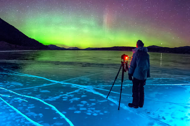 PIC BY DAVID SWINDLER/ CATERS NEWS - (PICTURED: Photographer David Swindler taking pictures of the northern lights) - These amazing pictures of frozen ice bubbles lit up by the Northern Lights will take your breath away. The stunning pictures show the perfectly frozen bubbles just under the surface of the water, spectacularly illuminated by the eerie green glow of the Northern Lights. The incredible snaps were taken by photographer David Swindler, from Utah, US, at Abraham Lake in Alberta, Canada. David, 36, said: We had a great time photographing the ice bubbles. SEE CATERS COPY.