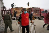 Workers and volunteers wearing face masks move bed parts into a makeshift hospital which has been converted from an office building to treat patients with the novel coronavirus disease (COVID-19) in Suifenhe, a city of Heilongjiang province on the border w