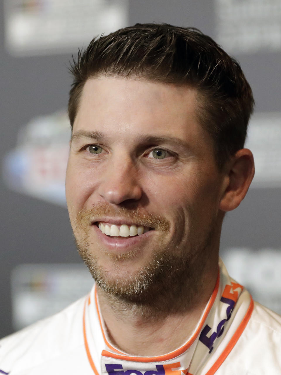 Denny Hamlin smiles during NASCAR Daytona 500 auto racing media day at Daytona International Speedway, Wednesday, Feb. 12, 2020, in Daytona Beach, Fla. Picking the car number for Michael Jordan's new NASCAR team was a slam dunk: Bubba Wallace will drive the No. 23 car when the team makes its debut next season. Jordan and Hamlin announced last month they had formed a NASCAR team with Bubba Wallace as the driver. (AP Photo/John Raoux)