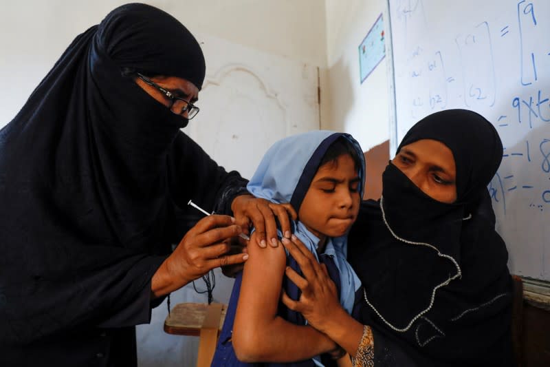 FILE PHOTO: A student reacts as she gets a free anti-typhoid vaccine during the immunisation campaign at a school in Karachi